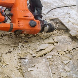 Demolition of old tiles with jackhammer. Renovation of removes old tiles from floor